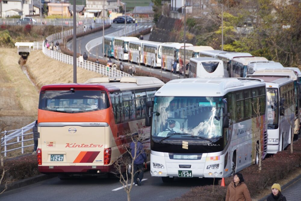 駐車場に入る待機列を横目に出発していく名阪近鉄バスの日野セレガ